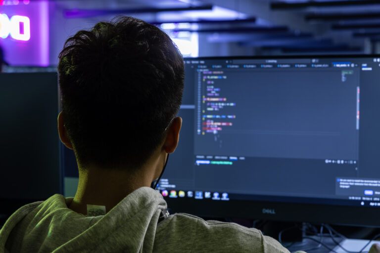 Étudiant de dos avec des écouteurs, qui est en train de coder sur un projet